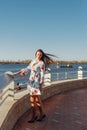 Dynamic fashion style Portrait of a young beautiful girl walking along the waterfront of the city