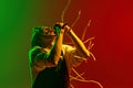 Dynamic image of artistic, soulful young man with dreadlocks, musician singing solo against gradient red green