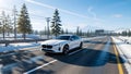 Pure Power: White EV Soars Through Winter Mountain Highway Royalty Free Stock Photo