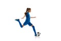 Dynamic image of teen girl, football player in blue uniform training, in motion with ball isolated on white studio