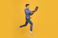 Dynamic image of teenage boy jumping and holding an open laptop