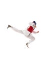 Dynamic image of young competitive girl in dobok and helmet training taekwondo isolated over white background. Fighter