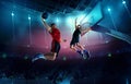 Dynamic image of young men, professional basketball players in motion, in a jump with ball under basket on 3D arena. Top Royalty Free Stock Photo