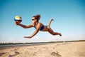 Dynamic image of young woman in motion, playing beach volleyball, hitting ball and falling down on sand. Sunny warm day Royalty Free Stock Photo