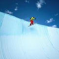 Snowboarder Performing a Jump Trick Against a Bright Blue Sky in Halfpipe Royalty Free Stock Photo