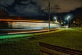 Dynamic Night Cityscape with Speeding Tram Light Trails and Green Park Foreground Royalty Free Stock Photo