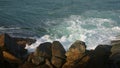 Waves crash against rugged rocks on coastline. Dynamic ocean swells, coastal landscape in view. Natural seascape