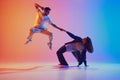 Dynamic photo of man leaping, woman bending backwards against vivid pink-blue gradient background. Energetic dance pose. Royalty Free Stock Photo