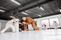 Dynamic portrait of man, professional judo, jiu-jitsu coach training with little boy, child in white kimono. Kids doing Royalty Free Stock Photo