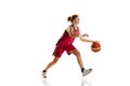 Dynamic portrait of teen girl, basketball player dribbling ball, playing over white studio background. Concept