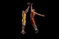 Dynamic portrait of two young men, professional basketball players in a jump, throwing ball into basket isolated over Royalty Free Stock Photo