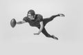 Dynamic portrait of young man, american football player catching ball. Black and white photography. Full equipment Royalty Free Stock Photo