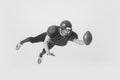 Dynamic portrait of young man, american football player in uniform training, catching ball. Black and white photography Royalty Free Stock Photo