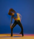 Dynamics. Portrait of young girl dancing heels dance over blue background in neon light with mixed lights. Concept of Royalty Free Stock Photo