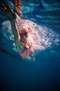 Dynamics. Young sportive woman, professional swimmer training in swimming pool indoor. Wearing cap and goggles Royalty Free Stock Photo