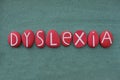 Dyslexia, reading disorder, composed with red colored stone letters over green sand