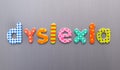 Dyslexia word spelled out in bright colorful patterened letters on brushed metal background