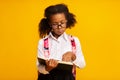 Dyslexic Schoolgirl Reading Book Standing Over Yellow Background, Studio Shot