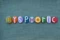Dysphoric, creative text composed with multi colored stone letters over geen sand Royalty Free Stock Photo