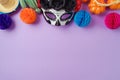 DÃÂ­a de los Muertos day of the dead holiday concept. Sugar skull mask and Mexican party decorations on purple background. Top view