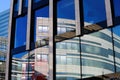 View on isolated glass facade with mirror image of curved modern building and blue sky Royalty Free Stock Photo