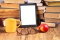 E-book, cup of coffee and glasses next to a stack of vintage books in the library. Space for text