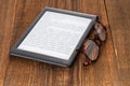 e-book reader and glasses on a wooden table Royalty Free Stock Photo
