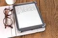 e-book reader and glasses on a wooden table Royalty Free Stock Photo