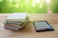 E-book reader and stack of books on wooden table Royalty Free Stock Photo