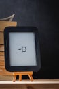 E-book reader on the wooden stand next to the stack of paper books at the black background Royalty Free Stock Photo