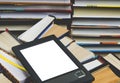 The e-book with a white screen lies on the open multi-colored books that lie on a dark background, close-up Royalty Free Stock Photo