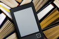 The e-book with a white screen lies on the open multi-colored books that lie on a dark background, close-up Royalty Free Stock Photo