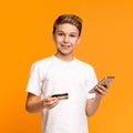 Cute teenager using mobile application and credit card Royalty Free Stock Photo