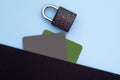 Protection of personal information. Black and green bank credit, debit card and metal lock on blue background. Flat lay, top view. Royalty Free Stock Photo