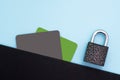 Protection of personal information. Black and green bank credit, debit card and metal lock on blue background. Flat lay, top view. Royalty Free Stock Photo