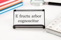 E fructu arbor cognoscitur the phrase in Latin translates as the Tree is known by its fruits on a white business card on a table