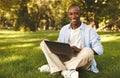 E-learning. African american student guy using laptop outdoors, having distant online lecture, sitting on grass in park Royalty Free Stock Photo