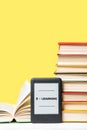 E-learning. E-book reader and a stack of books on a yellow background. Vertical. Copy space. Concept of education and electronic Royalty Free Stock Photo