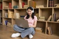 E-learning. Happy asian lady studying online, wearing headphones and using laptop computer at home, copy space Royalty Free Stock Photo