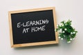 E-LEARNING AT HOME text in white chalk handwriting on a blackboard Royalty Free Stock Photo