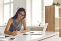 Student in glasses taking notes while watching webinar or listening to online lecture on laptop Royalty Free Stock Photo