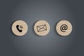 E-mail address ,telephone number and letter icons print screen on circle wooden block on table.