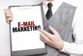 e-mail marketing inscription on a notebook in the hands of a businessman on a gray background, a man points with a finger to the