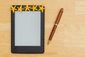 An e-reader on a wood desk with a pen and five gold stars Royalty Free Stock Photo