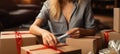 E-shopping arrangement: Woman thoughtfully assembles package for Cyber Monday\'s shopping frenzy.