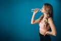 Strong girl drinking fresh water over blue studio background Royalty Free Stock Photo