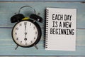 Each day is a New Beginning text written on notepad with alarm clock on wooden background Royalty Free Stock Photo