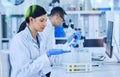 Each dosage, carefully measured. an attractive young female scientist working in her lab with a colleague in the