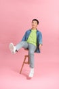 Eager smart casual man looking away sitting on a stool on pink studio background Royalty Free Stock Photo