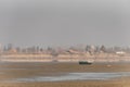 An eagle fisherman flying and searching for his prey, a boat on a dry lake